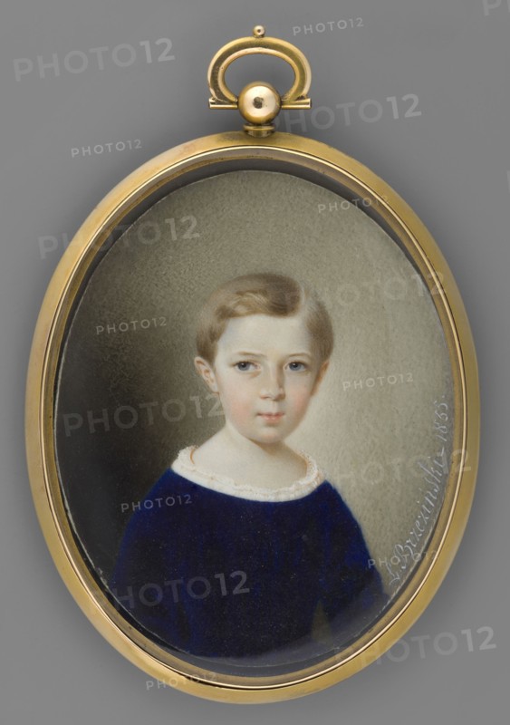 Portrait of a Child. Leon Brzezinski 1809–1865, painter. Portrait of a Girl, half-length, slightly to the right. Light ash-blond hair, short, parted on the side. At the neckline a hem of white lace from a blouse or shirt is visible; sapphire velvet dress with long sleeves. Grey-olive background, significantly darkened at the bottom left. Framing: gilded bronze frame, pendant, medallion type. Inscribed: L. Brzezinski - 1855. Miniature, height 8.5 cm, width 6.8 cm. Subjects: boys; children; portraits en three-quarters; Polish miniature., An oval gold-colored pendant containing a painted portrait of a young child with light brown hair and a fair complexion, wearing a dark blue garment with a pale collar, set against a neutral grayish-beige background; the pendant has a rounded top loop and a small spherical knob, and the overall colors visible include gold, gray, beige, light brown, fair skin tones, dark blue, and pale off-white.