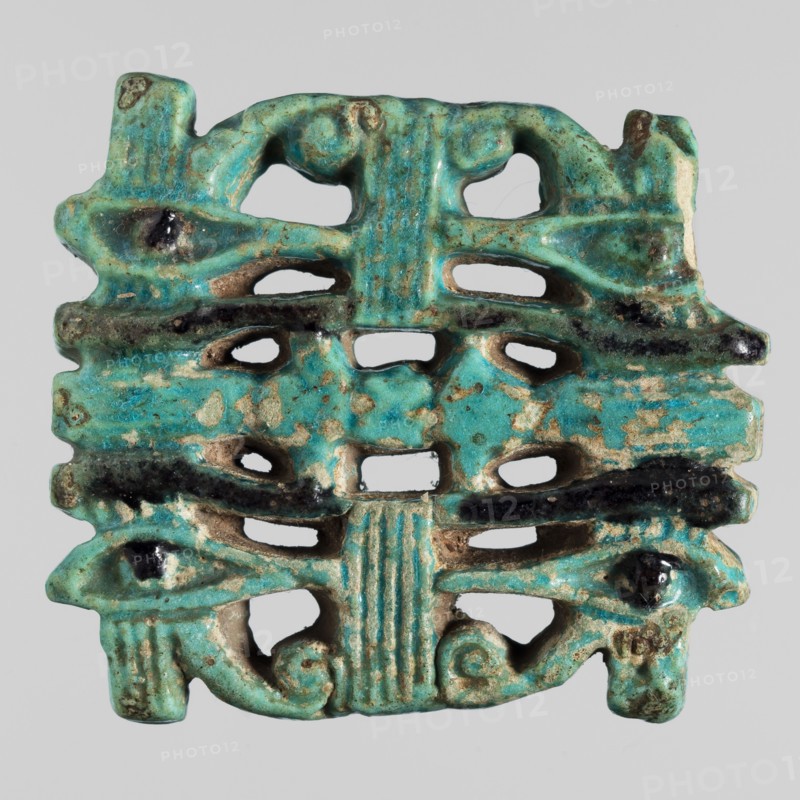 Amulet - quadruple udjat eye;, Openwork plaque with pairs of eyes separated by columns; udjat eyes; Egyptian religion; grave goods; mummies; ca. 747–656 BC, Third Intermediate Period, 25th Dynasty, Egypt; amulet; height 4.1 cm, width 4.8 cm, The image shows a small decorative object with a perforated, symmetrical form and a weathered surface; its dominant color is turquoise with areas of darker teal and black accents and patches where the underlying beige material is exposed, and there are traces of brownish discoloration; the piece features rounded protrusions, curved cutouts, and ridged vertical elements, with an overall rectangular outline and irregular edges.