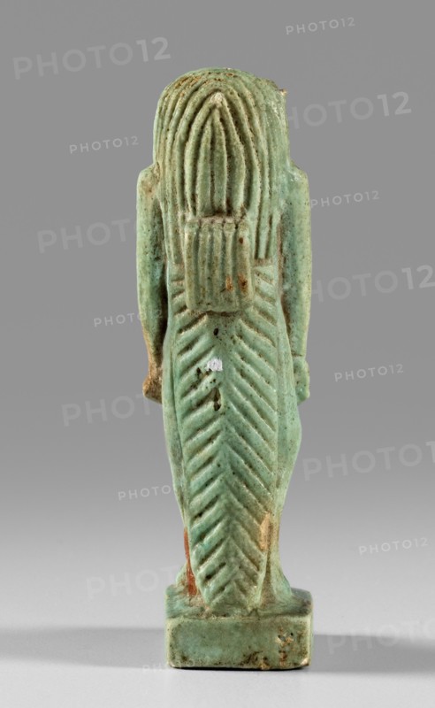 Amulet — goddess Toeris. Figurine of the goddess Toeris in the form of a pregnant hippopotamus standing on lion legs and equipped with a crocodile tail; a stand under the legs and a pendant on the back. Egyptian deities; crocodiles; hippopotamuses. 664–332 BC, Late Period, Egypt. Amulet; height 5 cm, width 1.5 cm., A small carved figurine viewed from the back, primarily pale turquoise-green with areas of darker green and patches of brownish and creamy wear, standing on a rectangular base; the figure has long, stylized hair or a headdress with vertical grooves and a long back piece carved with chevron-like ridges, and the surface shows small spots of discoloration and tiny pits.