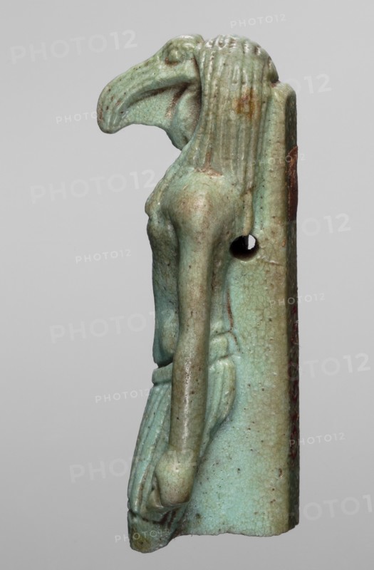 Amulet - god Thoth; maker, Thoth myth., Egyptian deities, Egyptian religion; dated 664–525 BC, Late Period, 26th Dynasty, Egypt; amulet; height 5.2 cm, width 2.1 cm, A small sculpted figure viewed in profile with a stylized bird-like head and elongated beak, a slender upright torso, and long straight arms hanging alongside a simple wrapped skirt; the surface shows a worn, glazed appearance in shades of turquoise and pale green with areas of brown and darker speckling, and there is a vertical back piece attached with a circular hole visible near the shoulder.