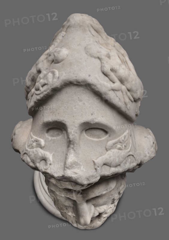 Head of Menelaus from the Menelaus Carrying the Body of Patroclus group, unknown artist. Head of a bearded man wearing a helmet, with an expressive face shown by wide-open eyes and parted mouth, emphasized by chiaroscuro effects from the contrast between lush locks of beard and hair emerging from under the helmet and the smooth skin of the face—the visage of a man experiencing dramatic moments. The helmet is adorned with relief decoration depicting fantastic creatures: on each side a centaur fighting a Greek, and below on the edge a triton figurine. The sculpture is a Roman copy of the head from a Hellenistic bronze composition depicting Menelaus with the body of Patroclus. Menelaus, Helen's husband, is depicted retrieving and carrying Patroclus's body after his death—a key episode in the Trojan War. Commonly reproduced in Roman sculpture. Dated to the 1st half of the 2nd century AD reign of Hadrian, 117–138. Roman Empire; sculpture; weight 78.5 kg., A stone sculpture of a head shown a...
