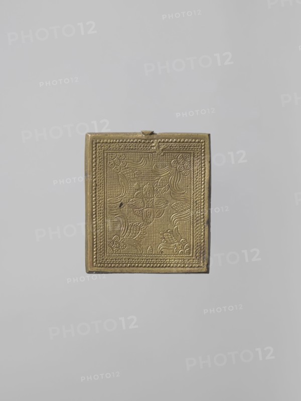 Icon: Our Lady of Tikhvin, Old Believers workshop, Our Lady of Tikhvin iconography, Mary mother of Jesus Christ, Jesus Christ Bible, icons, ornaments, Our Lady and Child iconography, maphorion iconography, inscriptions, unknown provenance. The icon represents a canonical variant of the Tikhvin image. The depiction of the figures, especially their faces, is somewhat archaizing. In the background of the image of the Mother of God with the Savior on her left shoulder, a schematic geometric pattern is marked. Inscriptions: MP OY, IC XC. On the reverse — a stylized floral-geometric ornament. 18th century, Russia. Height 5.8 cm, width 5.2 cm., A small rectangular ornate box in a metallic gold color is centered against a plain light gray background; the box surface has an embossed decorative pattern with floral and curving motifs framed by a textured border, and the edges of the box show slightly darker golden tones and minor wear.