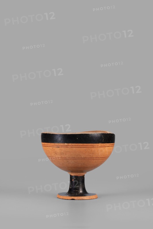 Fragment of a lydion. Archaic period; 2nd half of the 6th century BC based on analogies, usually dated mid–late 6th century BC; examples dated c. 550–525 BC and broadly 6th century BC. Asia Minor possibly. Vessel type: lydion; function: toilet vessel. Fragmentarily preserved foot and lower part of the body. Foot flat, disc-shaped, conically recessed at bottom; medium-high cylindrical foot tapering slightly toward the bowl. Preserved part of bowl hemispherical. Top of the foot, the foot, and upper parts of the bowl covered with glossy varnish; remaining parts clay-colored. Outer surface of bowl decorated with four horizontal thin lines in light brown. Interior not smoothed, with visible turning traces. Outer part of foot covered with matte varnish. Materials/technique: thin-walled Eastern Greek ceramics; varnish color 10 YR 2/1 black; ornament colors 2.5 YR 4/3 reddish brown and 2.5 YR 4/6 red; clay color 5 YR 6/6 reddish yellow. Dimensions: height 7 cm; width 7.7 cm; weight 0.132 kg., ...