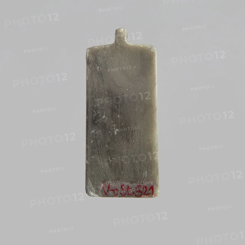Tile with pseudo-hieroglyphs; scarab with pseudo-hieroglyphs on the base; 20th century; Egypt; forgery; scarab amulet; height 0.9 cm, width 2.4 cm, depth 1.4 cm., A rectangular, slightly worn object with rounded top edges and a small protrusion at the center of the top, shown against a light gray background; the object has a smooth, scratched surface with a metallic gray and brownish tone, subtle darker gray areas, and a few small lighter specks, plus a small area of red near the bottom edge.
