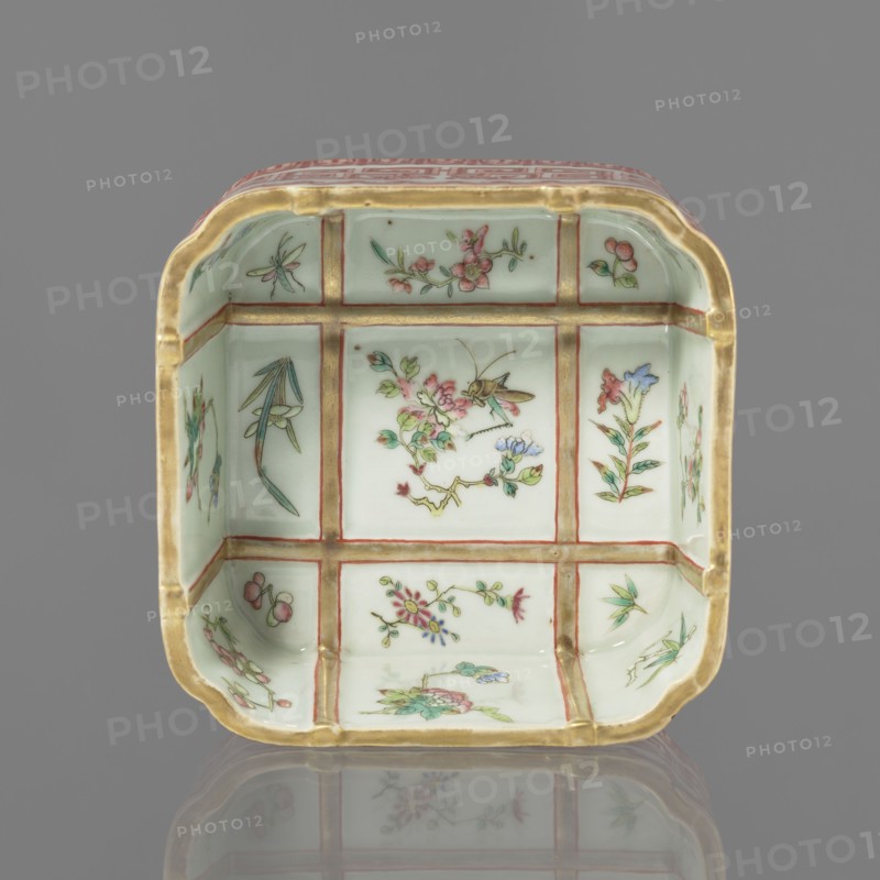 Vessel, Chinese, Qing dynasty Daoguang, 1821–1850, porcelain, colored; decorated on the outside with lambrequin ornament, floral decorations, and meander strip. Vessel; height 6.0 cm, width 12.8 cm., A square ceramic dish with rounded corners and a pale green interior divided visually into a grid by raised golden lines, each panel painted with delicate floral and insect motifs in colors including pink, green, blue, red, and gold, with the gold rim showing around the top edge and a reflection of the dish visible on a smooth gray surface; the background behind the dish is solid gray.