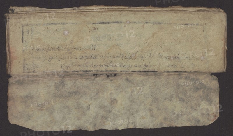 Buddhist text - Formula of repentance Tib. sdig bshags gser gyi spu gri bzhugs so. Buddhist art, Tibetan. Book in the Tibetan pecha style; xylographic print in the disciple script dbu can. 16 folios; folio numbering 2-15 recto, first verso. Print on thin handmade paper, clear translucency. 19th century, Tibet. Graphic. Width 25.5 cm; height 7.8 cm., An aged, folded sheet of paper or parchment lies against a dark background, showing a top flap with a textured, yellowed surface and a lower flap with a mottled, fibrous appearance; the top area has several faint smudges and darker grayish marks, a few small round discolorations, and subtle worn edges while the lower area displays cloudy gray, beige, and brown variations with visible fiber patterns and slightly rounded corners, and the entire object exhibits signs of creasing and uneven margins.