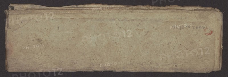 Buddhist text - Formula of repentance Tib. sdig bshags gser gyi spu gri bzhugs so, author unknown. Book in the Tibetan pecha style, xylographic print in the disciple script dbu can, 16 folios folio numbering 2–15 recto, first verso. Print on thin handmade paper, clear translucency. 19th century, Tibet. Graphic prints; width 25.5 cm, height 7.8 cm., A worn rectangular object with a textured surface lies against a dark background; its surface shows a weathered, uneven tan and beige coloration with areas of light brown discoloration and faint darker spots, and there is a small reddish mark near one corner. The edges are frayed and layered, showing a few folded and creased sections and some rough, darker brown along the top and sides. The overall appearance is aged and fibrous with subtle variations of cream, tan, beige, light brown, and a hint of reddish color.