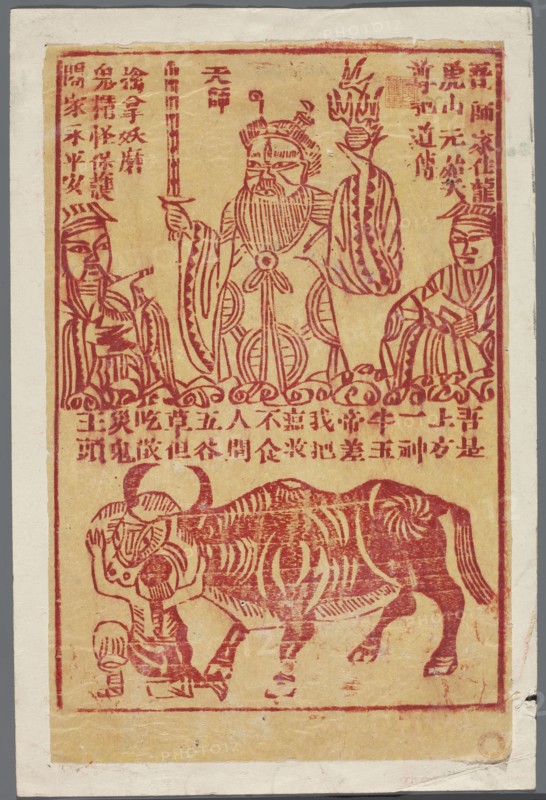 Amulet against diseases, nianhua New Year's picture woodblock print, zhan dian shi amulet, graphic print, early 20th century, China; height 25.6 cm, width 17.1 cm., The image shows a rectangular print with a beige background and red ink illustrations; a central standing figure with a long beard and ornate robe holds a vertical object in one hand and a flaming or decorative object in the other, flanked by two smaller seated figures wearing patterned robes and headpieces; below them a group of stylized curved decorative motifs separates the upper scene from a lower scene featuring a large, striped bovine figure standing over a smaller kneeling human-like figure; the print is bordered by a red rectangular frame and sits on a wider off-white margin with slight wear and creases at the edges; visible colors include beige, red, off-white, and small areas of grayish discoloration.
