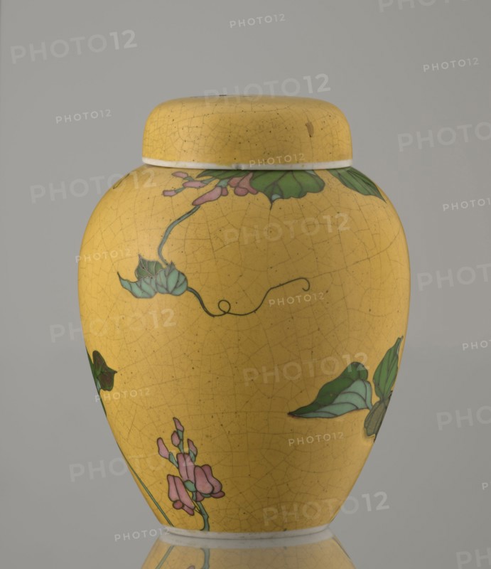 Ginger vessel with lid, Nagoya Shippô Kaisha c. 1870–1880, Meiji period. Small ovoid porcelain vase with a round flattened lid. Exterior covered with a lemon-yellow glaze with a decorative grid of crackles; interior and bottom white with transparent glaze. Decorated with a naturalistic bean-vine motif of greenish-brown leaves and pink flowers, twining around the body and reaching the lid. Motif executed in cloisonné enamel using brass wires and multiple shades of enamel; motif was carved into the vessel’s surface prior to enameling totai-shippo technique. Porcelain cloisonné technique developed around 1868 by Tsukamoto Kaisuke; similar wares also made by Takeuchi Chubei and Suzuki Seiichiro; Takeuchi Chubei was among prominent craftsmen employed by Nihon Shippo Kaisha and this piece may be by him though unsigned. Signature in cobalt underglaze: Nihon Shippo Kaisha sei zo; overglaze red iron rhomboid cartouche with the sign sho. Nagoya, Japan. Vessel; height 12.4 cm, diameter 9.6 cm. Cl...