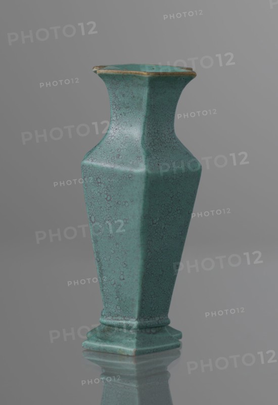 Vase, Qing style; ceramics; Chinese, Qing 1644–1911, 19th century; vessel; height 11.6 cm, width 4.7 cm, depth 7.15 cm., A tall hexagonal vase with a flared neck and a stepped base, shown standing on a reflective surface; the vase has a crackled glaze texture and is predominantly turquoise with darker teal speckling and subtle brownish accents along the rim and edges, set against a smooth gray background.