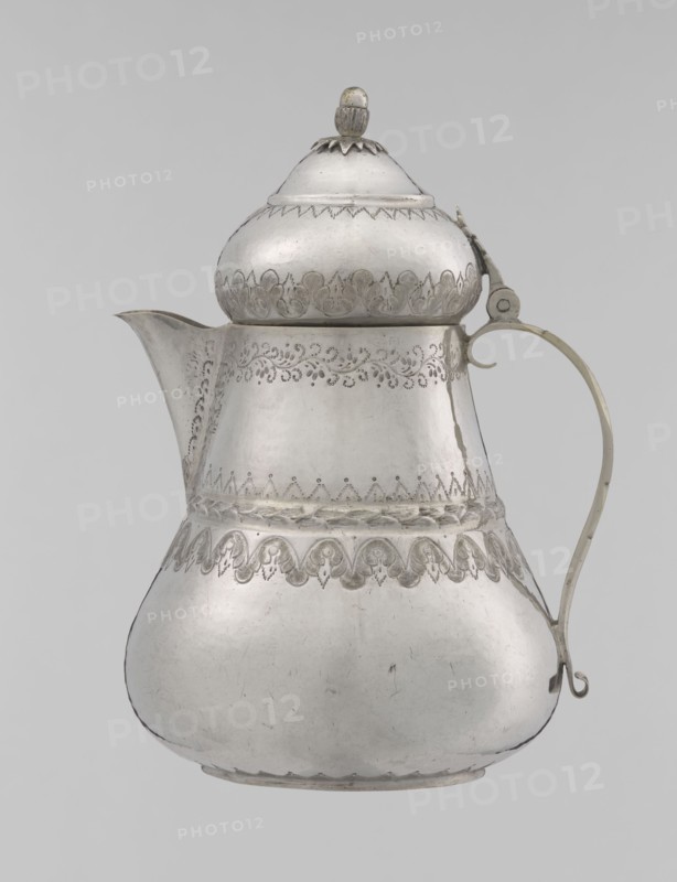 Teapot; maker, 19th century, Turkey Ottoman dynasty, 1299–1922; Islamic art, Turkish; silver vessel; teapot/jug form; height 17.0 cm, diameter 10.9 cm, weight 320 g; decorated with geometric motifs, plant ornament including lambrequin, zigzag patterns., A silver-colored metal pitcher with a bulbous lower body tapering to a narrower midsection and a rounded lid topped by a small finial, featuring engraved decorative patterns around the midsection, near the top, and along the lower shoulder; a curved spout extends from one side and a thin, curved handle with a small curled end attaches on the opposite side; the surface shows areas of slight tarnish and subtle scratches, and the background is a pale gray.