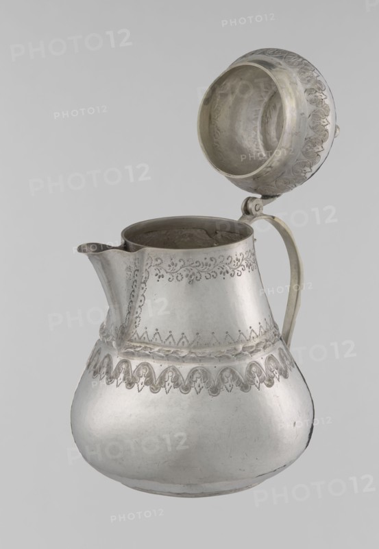 Teapot, 19th century; Ottoman dynasty 1299–1922; Turkish, Islamic art; vessel teapot/jug; materials not specified; decorated with geometric motifs, plant ornament, zigzag, lambrequin; height 17.0 cm, diameter 10.9 cm, weight 320 g; Turkey place of origin., A metal pitcher with a hinged lid shown open, with a bulbous lower body and narrower upper body, a curved spout on one side and a handle on the opposite side; the surface has engraved decorative patterns around the upper body and near the midsection, and the lid interior is visible with matching decorative detail; visible colors include silver, gray, and subtle darker gray areas from shading and wear, against a light gray background.