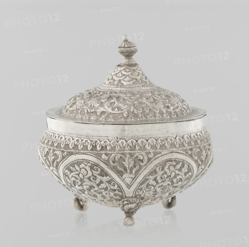 Vessel with a lid, Islamic art, Turkish, Ottoman dynasty 1299–1922, plant ornament, flowers, plant tendril, marked coat of arms, 19th century, Turkey, vessel, weight 240 g, height 11.7 cm, diameter 10.5 cm, An ornate lidded bowl with an embossed surface rests on a plain light background; the bowl and lid are decorated all over with raised floral and foliate patterns and scrolling motifs, with a conical lid topped by a finial and the body standing on a few rounded feet; the visible colors are silver and shades of gray.