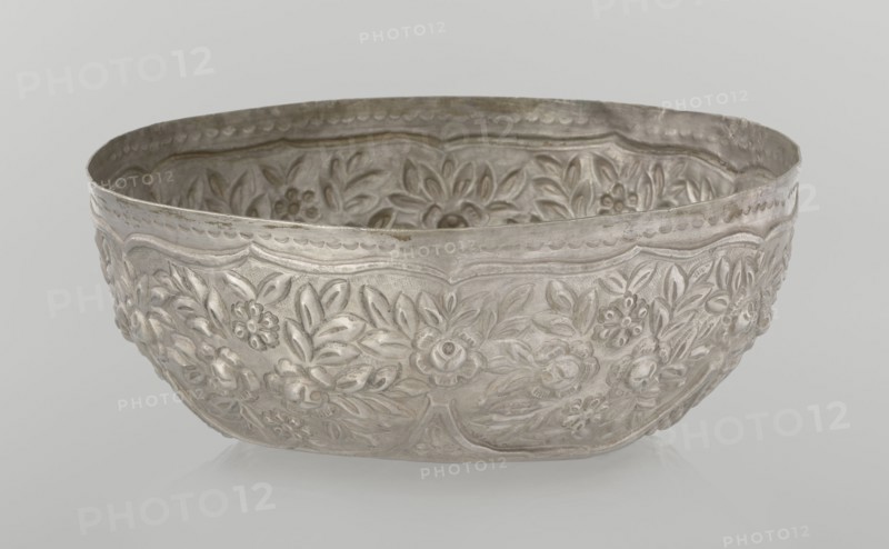 Bowl, late 19th century, Turkey; Ottoman dynasty 1299–1922; vessel, height 7.0 cm, diameter 18.0 cm, weight 295 g; Islamic art, Turkish; decorated with floral and plant motifs, wall decorated with floral motifs in the valance., A shallow metal bowl with an embossed floral pattern covering its exterior and interior, showing raised flowers and leaves in a repeating decorative design; the rim is gently scalloped and the surface has a slightly worn, tarnished appearance. The visible colors are silver and gray with subtle darker gray areas where the metal appears aged.