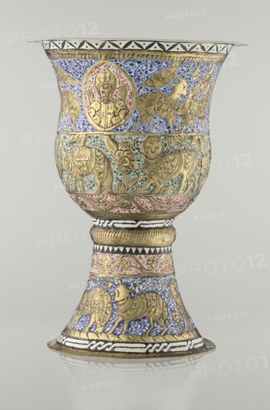 Cup, Persian, Qajar dynasty 1785–1925, 19th century, Iran. Ceramic vessel, height 25.5 cm, diameter 18.4 cm. Decoration: cartouches with a bust of a man, animals lions, birds, figures, flowers, geometric and small plant ornament; figurative motifs., A tall ornate cup with a flared rim and a flared base, decorated in gold relief with enamel colors; the upper bowl shows a band of blue enamel background with gold figures and a roundel containing a bearded human bust framed by red and gold, below that a band with green enamel and gold animal and floral motifs, and a narrow red and gold patterned band above the stem. The stem has a textured gold collar and black-and-white geometric detailing, while the lower flared foot displays blue enamel panels with gold animals and foliage, bordered by black-and-white bands and gold trim. The visible colors include gold, blue, green, red, black, white, and subtle beige from the metal, all set against a neutral light-gray background.