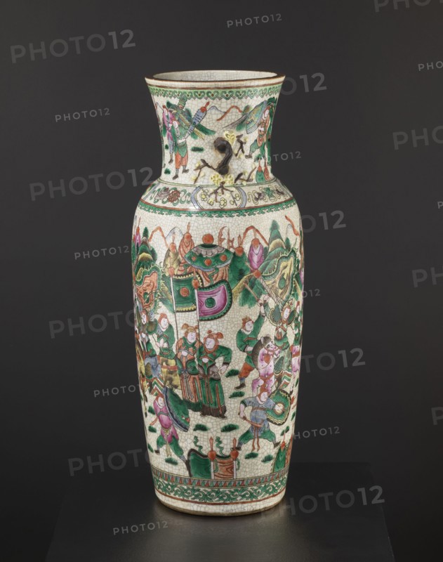 Vase, noted. Chinese, 19th century. Colored porcelain vessel, height 61 cm, diameter 19.6 cm. Slightly tapering toward the bottom with a thick neck slightly flared upward and two small handles shaped like a plum blossom branch. Body decorated with an elaborate battle scene of warriors on foot and on horseback; neck shows a dignitary surrounded by her entourage. Features figurative scenes, plant ornaments, horses, warriors, landscapes, and battle scenes., A tall ceramic vase with a crackled off-white surface decorated with ornate painted scenes in green, pink, red, orange, brown, black, and yellow hues; the vase has a flared neck and a rounded body with a decorative band near the top and bottom featuring green and brown patterns, and the main body shows a group of stylized figures and ornamental motifs, some wearing green and pink garments, surrounded by foliage-like shapes in green and brown, curved decorative elements in pink and green, and small ground accents in dark green, with a p...