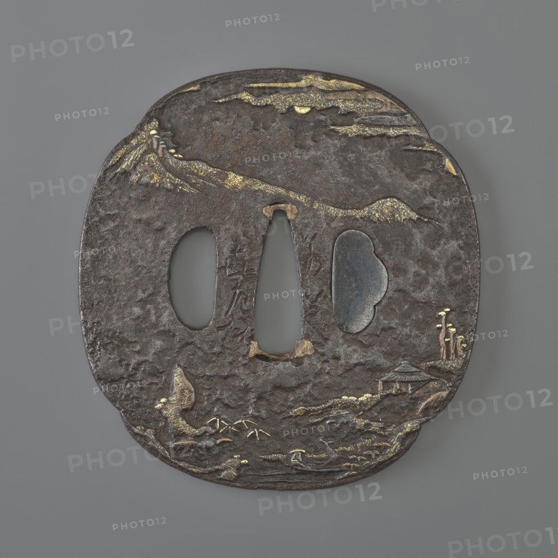 Crossguard tsuba. Maker: Jakushi; Kizaemon. Tsuba in the shape of a mokkô quatrefoil, with a kôgai hitsu hole plugged with shakudô, copper sekigane, textured surface ishime ji. Decoration in low relief hirabori with fine details inlaid with gold, using nunome technique in places, and copper. Both sides show a Chinese-style mountainous landscape with human and architectural staffage, including mountains, bamboos, pine trees, and bridges. Signed. 18th century Edo period, 1603–1868. Japan, Nagasaki, Hizen. Function: katana sword crossguard. Dimensions: height 7.6 cm; width 6.0 cm; depth 0.4 cm., A roughly oval, dark brown metal object with a textured, pitted surface and a few irregular cutouts in the center, showing a matte gray background through them; the piece has scattered areas of gold-colored inlay forming linear and patchy highlights along the top edge and parts of the lower half, and there are small raised and engraved motifs suggesting natural shapes across the surface rendered i...