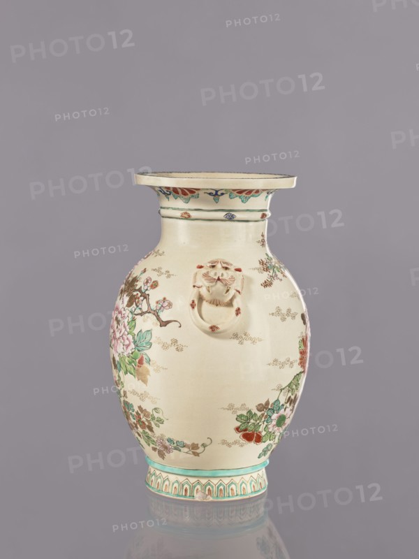 Vase, flowers, satsuma, Japanese art, vases, Japanese culture, ceramics, cracklework decoration, lions, floral decorations, peonies, chrysanthemums, plum trees, Meiji 1868–1912, ca. 1870–1880 Meiji 3–13, Japan, vessel, height 26.5 cm, width 17.5 cm, diameter 16.5 cm, A ceramic vase with a rounded body and a flared rim sits against a plain gray background, predominantly cream in color with decorative floral painting in green, pink, red, and blue, and small gold or brown dotted accents. The rim has a band of turquoise and red petal-like motifs, and the neck area shows thin green bands. A sculpted lion head with a ring is attached to the front of the vase in the same cream tone with small red accents. The main body features painted branches with leaves and blossoms in shades of green, pink, and red, along with brown stems and subtle gold or brown dotted cloud-like marks. The base has a turquoise band above a patterned border in turquoise, cream, and red. The surface shows a glossy finish ...