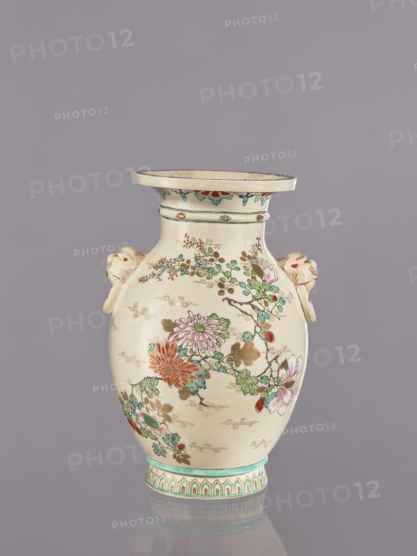 Vase, flowers, satsuma, Japanese art, vases, Japanese culture, ceramics, cracklework decoration, lions, floral decorations, peonies, chrysanthemums, plum trees, Meiji 1868–1912, ca. 1870–1880 Meiji 3–13, Japan, vessel, height 26.5 cm, width 17.5 cm, diameter 16.5 cm, An off-white ceramic vase with a wide flared rim and a rounded body sits against a muted gray background; the vase is decorated with painted floral branches featuring flowers in shades of pink, red, green, and teal with brown stems and golden-brown accents, and it has a turquoise band and patterned base in turquoise and red tones; there are sculpted animal head handles on each side in a pale beige with reddish details, and a decorative band of small colorful motifs runs beneath the rim.