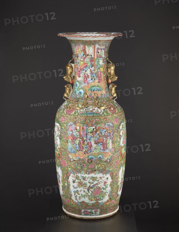 Vase, Chinese, 19th century, porcelain vessel decorated with figurative court scenes, butterflies, floral and plant ornaments; colored porcelain; height 93 cm, diameter 34 cm; China., A tall ornate porcelain vase sits against a dark background, predominantly decorated with green, pink, and gold hues along with accents of white, blue, and red. The vase has a flared rim with a scalloped edge, detailed painted scenes on the neck and body featuring small groups of figures and architectural elements rendered in bright colors, and ornate gilt handles on the neck shaped like stylized animal heads. The main body is richly patterned with floral and foliate motifs in green and pink, framed white panels containing painted floral and bird images, and intricate decorative bands encircling the shoulder and base, all set on a white porcelain ground with gold highlights.