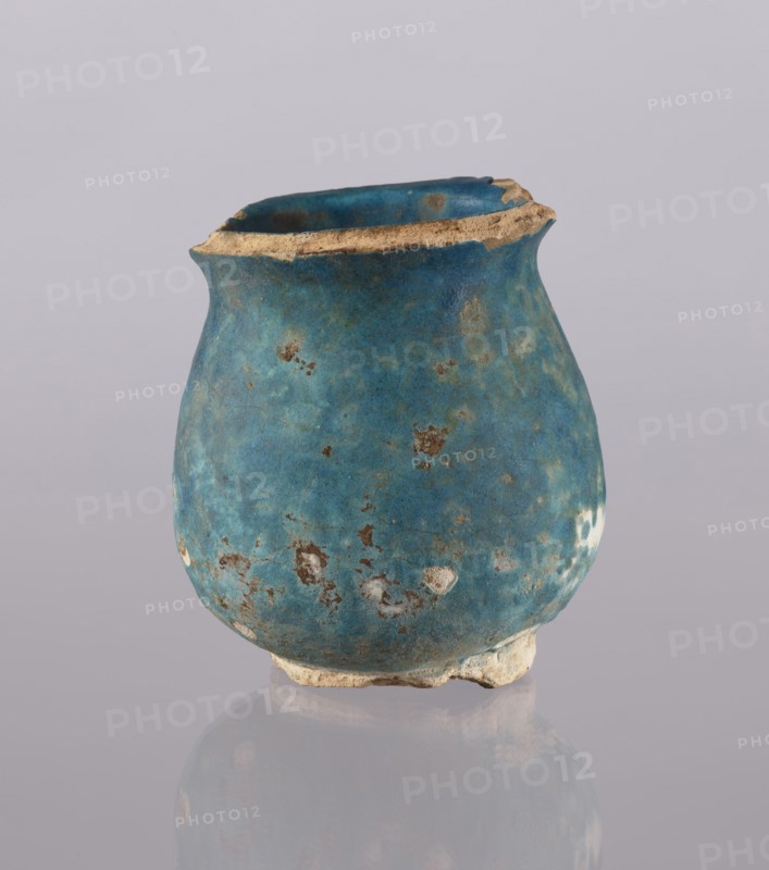 Jug, Abdullazad Mirza Baba fl. ante 1939, repossession noted, Islamic art, Persian culture, Ilkhanids 1256–1335, ceramics, vessel cup/vase, everyday life in the Middle East, 13th–14th century, Iran, weight 0.378 kg, height 12.5 cm, diameter 11.5 cm, A small rounded vessel with a worn rim sits against a plain pale background, its surface showing a rich blue-green patina with patches of lighter turquoise and areas of brownish corrosion; the rim and base reveal exposed beige material, and the vessel's exterior has several irregular spots where the blue finish has chipped away, creating a mottled texture and a slightly rough appearance.