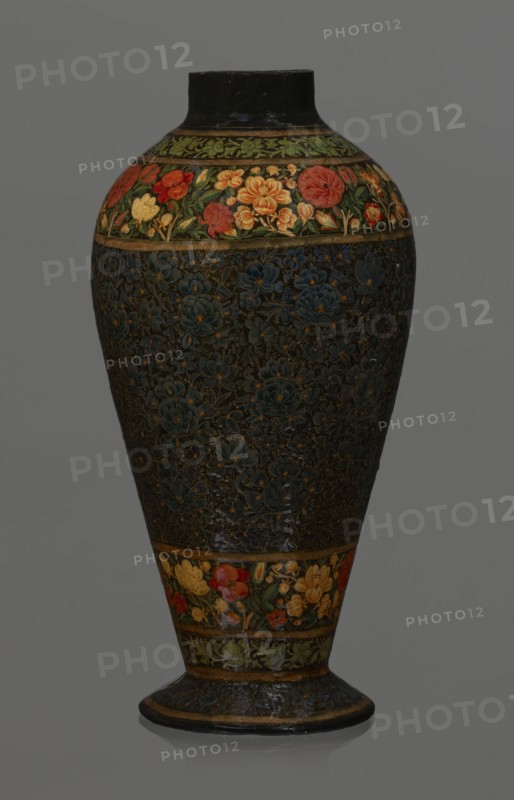 Vase, Qajar dynasty 1785–1925, Persian, Islamic art; lacquer vase, 19th century, Iran; vessel, height 32.0 cm, diameter 17.0 cm; decoration: densely placed plant motifs peonies with gold contouring; on the collar and above the foot flowers red and gold., A tall, rounded vase with a narrow neck and flaring base sits against a plain gray background; its surface features dense floral patterns with a dark, almost black background on the main body and bands of colorful flower decorations near the top and base. The decorative bands show a mix of red, orange, yellow, green and hints of lighter tones forming stylized blossoms and leaves, while the central dark area is filled with intricate raised floral motifs in deep blue and muted gold outlines. The neck and base edges are darker, appearing black with worn highlights, and the lower flaring foot echoes the dark floral texture with thin gold bands.