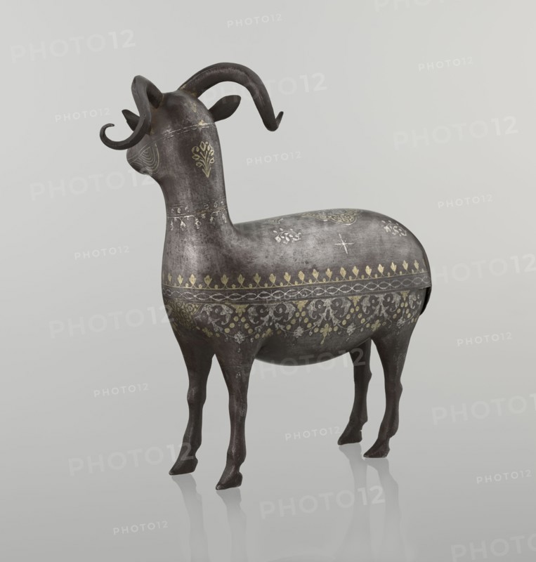 Ram, Islamic art, Persian, Qajar dynasty 1785–1925, sculpture; animal figurine of a ram with horns; decorated on the back with medallions and palmettes with floral ornament; 1st half of the 19th century, Iran; materials not stated; height 22.5 cm, width 20.5 cm, depth 9.0 cm, weight 0.64 kg., A sculptural animal figure with curved horns standing on a reflective surface, rendered in dark gray with a weathered texture and decorated with ornate patterns in gold and lighter gray; the figure has a rounded body, slender legs, stylized ears, and floral and geometric motifs across its neck, sides, and back, with visible highlights and shadowing against a pale gray background.