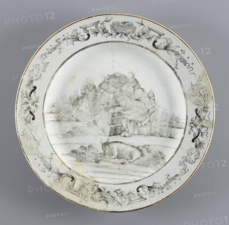 Plate with a scene of the adoration of the Holy Family the shepherds' adoration., Chinese, Qing dynasty 1644–1911, 18th century. Porcelain export plate painted in iron oxide black Chinese ink/soot. The plate depicts the popular export-porcelain motif of the arrival of the shepherds to the Bethlehem stable; iconography includes the Holy Family and the shepherds' adoration; Jesus Christ. Vessel; height 2.2 cm, diameter 23.0 cm, weight 0.37 kg., A round ceramic plate with a pale grayish-white background and a thin gold rim, decorated with delicate monochrome gray and black line drawings; the central scene shows a group of figures seated and standing amid draped fabric and architectural elements, with one reclining animal in the foreground and grassy foliage around the scene, while the wide border features scrolling floral and foliate motifs, ornamental cartouches, and ribbonlike flourishes in gray and black.