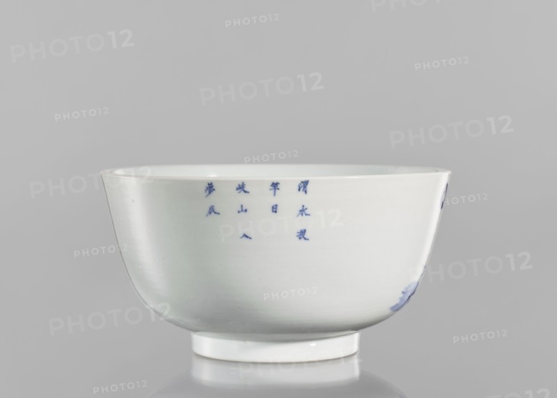 Bowl, ceramics, blue-and-white porcelain, Chinese, Qing 1644–1911, 19th century, South China, vessel, height 8.8 cm, diameter 17 cm. Decorated with landscape motifs: pines, trees, fishermen; inscribed with characters referencing the Wei River ??, Wèi Shui, ??? tóu gan rì, the day of casting the fishing rod, ?? Qí Shan, Mount Qi, and ??? rù mèng chén, entering a dream in the morning, evoking a peaceful, nostalgic scene., A white ceramic bowl with a glossy surface sits against a light gray background, showing a rounded body that tapers to a short circular foot and a gently flared rim; a group of small blue brushstrokes appears on the bowl's side and there is a smudge of blue near the base on one side, with subtle reflections and soft shadows on the surface.