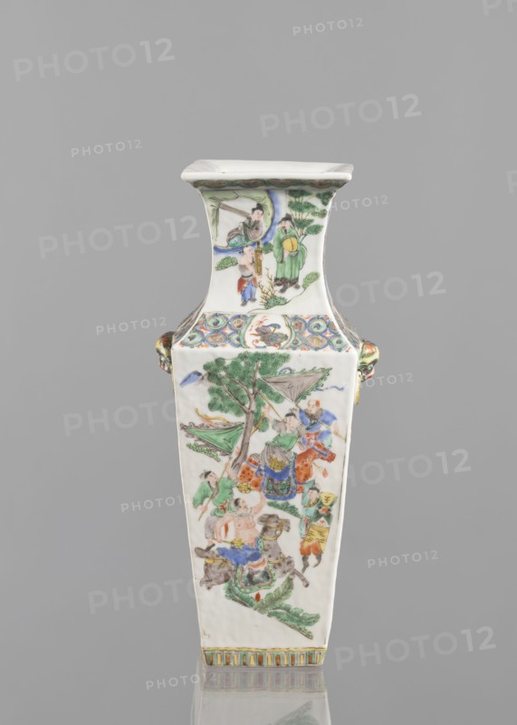 Vase, Chinese, 18th century. Porcelain, colored; figurative genre and battle scenes. Vessel, height 31.2 cm, width 11.0 cm., A tall, rectangular porcelain vase with a flared square rim sits against a plain gray background; the vase is predominantly white with detailed hand-painted scenes in green, blue, red, yellow, orange, and brown, showing figures in traditional clothing, trees, and animals on its front and neck panels; decorative patterned bands in blue, green, yellow, and orange encircle the neck and base, and small ornamental handles with green and orange accents appear on the sides.