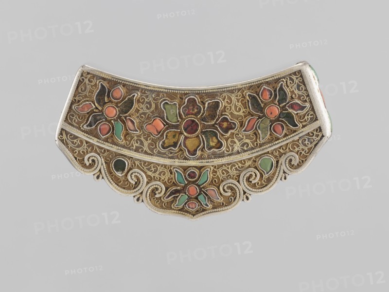 Braid clasp, maker, clasp for braids; jewelry; artistic craft; Mongolian women's ornament; 18th–19th century, Mongolia; dimensions: length 9.3 cm, width 4.5 cm, thickness 0.7 cm, height 0.7 cm., An ornate curved metal decorative object with intricate filigree work and scalloped lower edge, featuring floral motifs filled with inlaid pieces in colors including green, orange, coral, red, and black set against a golden-brown background with silver-toned edging and scroll details.