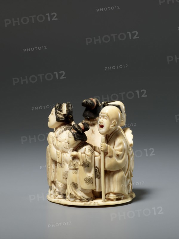 Okimono in the shape of a group of six singing people; unknown creator; Japanese, Meiji late 19th century; figurines, okimono, musicians; depiction: a courtesan with a small kamuro servant, a townswoman carrying a lantern, a wealthy merchant with a fan, a messenger with an oblong box, and a blind Buddhist monk with a shaved head leaning on a cane; sculpture; height 5.1 cm, width 5.2 cm, depth 4.5 cm., A small carved group of figures arranged in a circular composition, primarily in an off-white or cream color with darker brown and black accents; the figures wear flowing robes with carved patterns and textured hair, including a figure holding a staff and a figure with a rounded, open-mouthed expression; a few figures have hair styled in topknots or buns with dark coloring, and there are subtle brownish shading and fine engraved details on the robes and faces; the piece sits on a low round base and is photographed against a gradient gray background ranging from dark gray at the top to lig...