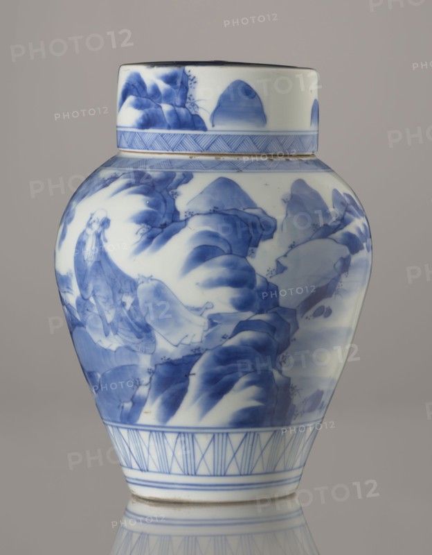 Storage vessel with lid, Zôshuntei Sanpo signed Zoshuntei Sampo zo, c. 1842–1878, Arita, Japan. Pear-shaped blue-and-white porcelain storage pot with flat cylindrical lid. Decorated in cobalt in several tones with a Chinese-style landscape: an old man resting under a pine on a rocky cliff overlooking a broad body of water, with a waterfall, lofty peaks, and distant sails; pines, mountains, waterfalls, and sages rendered in a style modeled on Chinese Southern School painting and related to the bunjinga nanga movement. Lower base band of three vertical and two crossed lines; diagonal-line ornamental bands forming triangular motifs at the neck and lid edge; lid decorated with a rock motif. Free-form painting with precise, masterful lines indicating an excellent porcelain decorator. Height 21.8 cm; diameter 15.3 cm., A porcelain jar with a lid shown against a neutral gray background, decorated in blue on a white ground; the jar has a bulbous body tapering toward a narrow base and a short c...