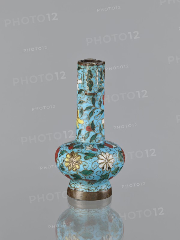 Vase, cloisonné enamel, gilding, Chinese, Qing dynasty 1644–1911, 19th century, China; plant ornament/decoration; vessel; height 13.0 cm, diameter 6.8 cm., A small ornamental vase with a long narrow neck and a rounded bulbous body sits against a plain gray background, covered in a bright turquoise glaze decorated with a floral cloisonné pattern in colors including yellow, white, red, green, and dark blue, with fine dark outlines and small scrolling vine motifs; the rim and base have metallic bands in a bronze tone, and the vase is reflected faintly on the glossy surface beneath it.