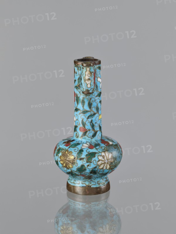 Vase, cloisonné enamel with gilding; Chinese, Qing dynasty 1644–1911, 19th century. Plant ornament/decoration. Vessel, height 13.0 cm, diameter 6.8 cm., A small vase with a long narrow neck and a rounded bulbous body sits upright against a plain gray background, decorated with an intricate floral and vine pattern in bright turquoise blue as the dominant color, accented with green leaves, red and white petals, and gold floral motifs, with darker metal bands at the base and rim and a subtle reflection of the vase visible beneath it.