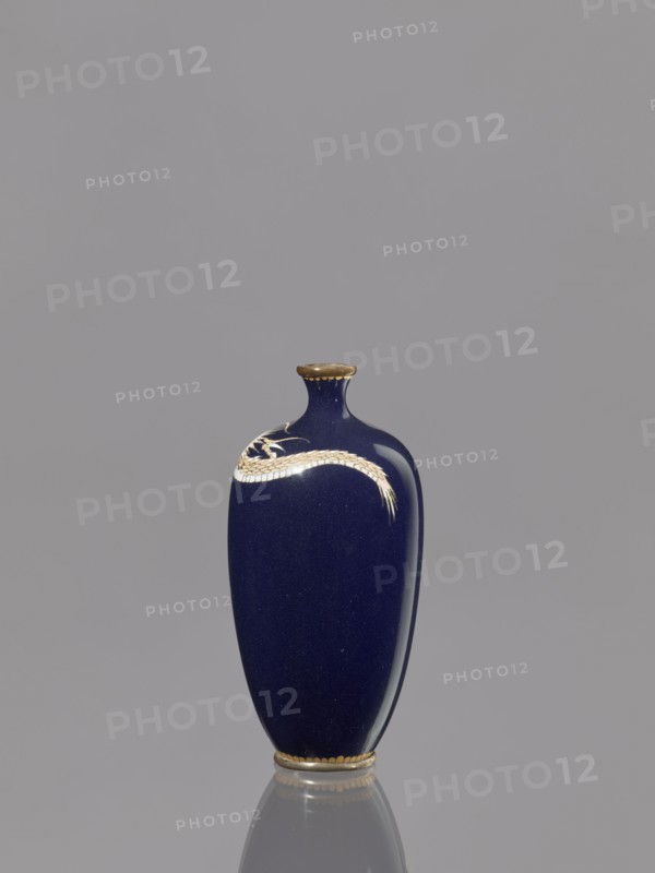 Vase, Meiji 1868–1912, cloisonné enamel, Japan, 19th/20th century; subject: Japanese dragons dragon motif/iconography; vessel; height 36.7 cm, diameter 4.6 cm., A tall vase with a deep blue glossy surface stands against a plain gray background, showing a smooth curved form with a narrow neck and small flared rim that is edged in a gold color; a gold-colored decorative motif resembling a sinuous band or stylized dragon wraps near the upper portion of the vase, and the base also has a gold-colored band; the vase casts a faint reflection on the surface below, and the visible colors are deep blue, gold, and gray.