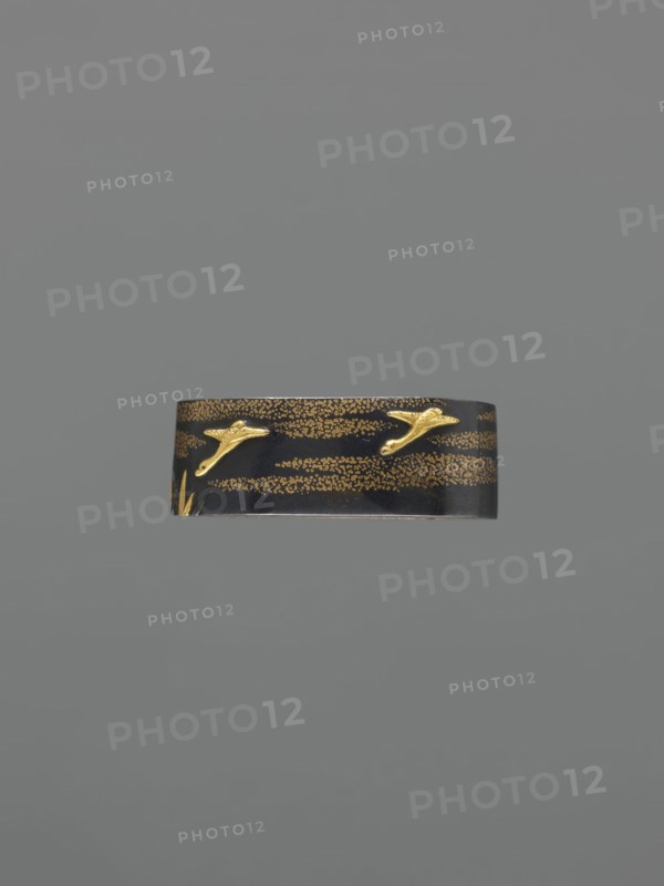 Metal collar ending a sword hilt fuchi, Nara, Toshinaga 1667–1736, Nara; Plastic decoration: wild geese among the clouds; 18th century Edo period, 1603–1868, Japan; fuchi; height 3.9 cm, width 2.2 cm, depth 1.2 cm; subject: geese and clouds; function: katana hilt fitting; material: metal., A dark band with a glossy black surface decorated with a pattern of small gold dots and a few raised gold bird-like shapes, set against a plain gray background.
