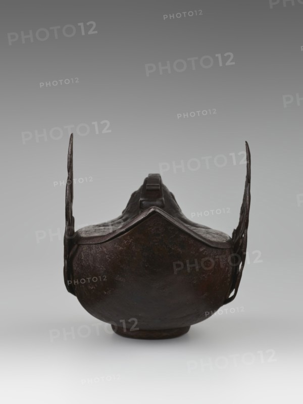 Duck incense burner, Chinese, Qing 1644–1911, 19th century, porcelain vessel in form of ducks with wings, function: incense burner, height 9.7 cm, width 13.6 cm, subject: ducks birds., An object resembling a dark brown, rounded metal vessel with a raised rim and a pointed front edge, flanked by two thin vertical extensions on either side; the surface appears uneven and textured with darker and lighter brown variations, and the background is a smooth gradient of gray transitioning from a darker gray at the top to a lighter gray near the bottom.