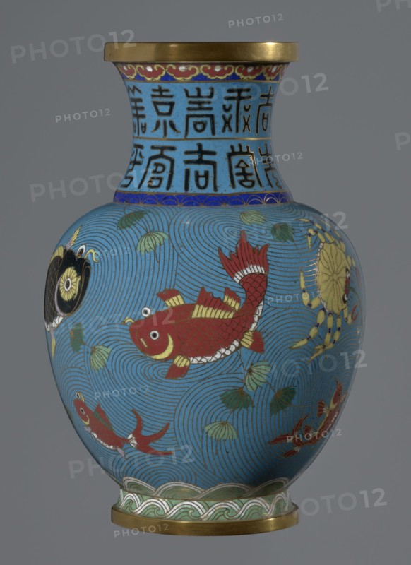 Vase;, Cloisonné enamel, 19th century China Qing dynasty. Vessel on a foot with a neck, height 23.2 cm, diameter 9.1 cm. Decoration: fish and crabs on a turquoise background, archaizing inscription on the neck. Chinese art; Qing style., A rounded vase with a flared rim and a narrow neck, decorated in bright enamel colors on a blue background; the body shows a large red fish with gold and white detailing, a few smaller red fish, a yellow crab, and a black and gold circular motif set against swirling blue wave patterns and scattered green leaves, the neck is banded with blue and gold decorative borders and vertical dark motifs, and both the rim and base have gold-colored metal fittings with a green and white wave-like border above the base.
