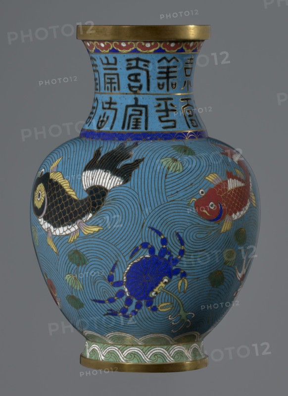 Vase, Chinese, Qing dynasty 1644–1911, 19th century. Cloisonné enamel on vessel on a foot with a neck. Decoration: fish and crabs on a turquoise background, archaizing inscription on the neck. Height 23.5 cm; diameter 9.3 cm., A rounded vase with a flared neck, primarily colored bright blue with darker blue concentric wave patterns across its body, features decorative bands near the top and base in gold and green tones. The neck area has a lighter blue background with black linear motifs; a narrow band of deep blue with gold accents separates the neck from the body. The body displays a group of colorful aquatic creatures: a black and gold fish with white and yellow fins, a red and gold fish with white accents, and a vivid blue crab with gold and white detailing. There are also several green leafy elements and small white accents scattered among the wave patterns. The rim and base edges are metallic gold, and the lowest decorative band includes green and white wave-like motifs. The over...