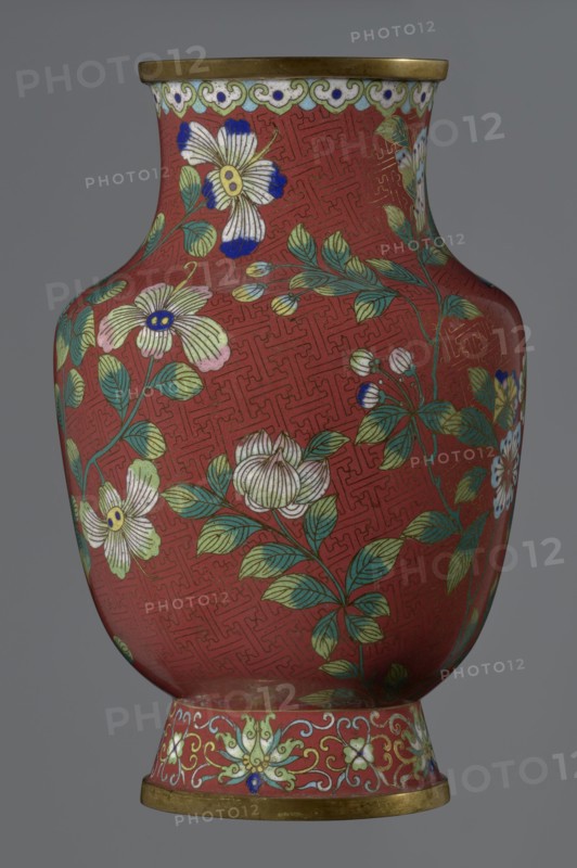 Vase, : Paderewski, Ignacy Jan 1860–1941. Chinese; Qing dynasty Xianfeng period, 1851–1861, 1st half of the 19th century. Cloisonné enamel vessel. The vase is set on a tall, conical foot flaring downwards and terminating in a metal ring, decorated with a lotus tendril. The neck is short and wide, topped with a metal ring, below which is a border composed of ruyi-heads. The belly and neck are decorated all around with a composition of flowers and plum branches against a red Chinese meander background. Height 25.1 cm; diameter 16.5 cm; weight 1.5 kg., A rounded vase with a narrow neck and flared rim decorated with floral motifs on a red background; the surface shows a repeating geometric pattern in a slightly darker red, and branches with green leaves and blossoms in white, pale yellow, pink, and blue spread across the body; the rim and foot have gold-colored bands, and the foot area features an ornate floral border in pale green, white, yellow, and blue against the red; overall colors v...