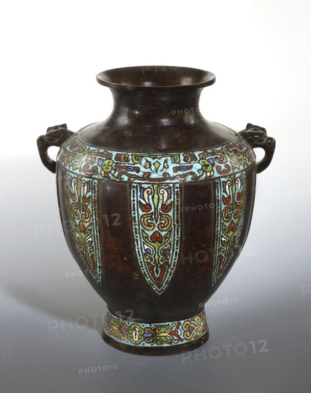 Vase with two handles, Chinese, Qing dynasty 1644–1911, 19th century. Cloisonné and champlevé enamel vessel decorated with cicadas and dragons. Height 31 cm; diameter 23.8 cm., A rounded vase with a wide flared neck and a narrow foot sits against a light background, its surface predominantly dark brown with areas of worn sheen. A decorative band near the shoulder and another around the foot feature ornate enamel patterns in turquoise, pale green, red, blue, and gold, forming repeating vertical panels that extend down the body. The vase has a pair of short handles on opposite sides shaped like stylized animal heads in the same dark brown material. The overall appearance combines the deep brown base color with bright accents of turquoise, pale green, red, blue, and gold in intricate curving designs.
