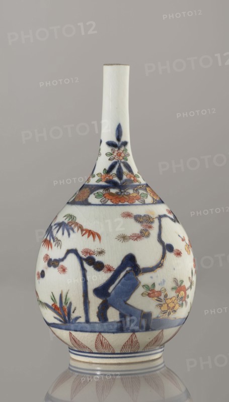 Bottle, porcelain with painted bamboos, pines, plums and sake motifs in Imari palette, Three Friends of Winter imagery, Arita, Japan, ca. 1700–1730, height 22.3 cm, diameter 12.2 cm., A porcelain bottle-shaped vase with a long narrow neck and rounded body, predominantly white with decorative painted motifs in blue, red, orange, green, and gold; the neck shows blue floral patterns and small green leaves, the shoulder has a band of blue and orange floral ornament, the body features a landscape-like scene with blue rocks or stylized forms, branches and foliage in blue and red, clusters of orange and yellow flowers with green leaves, and scattered red starburst-like blooms, a decorative band of red leaf shapes around the base, and subtle crazing in the glaze visible across the surface.