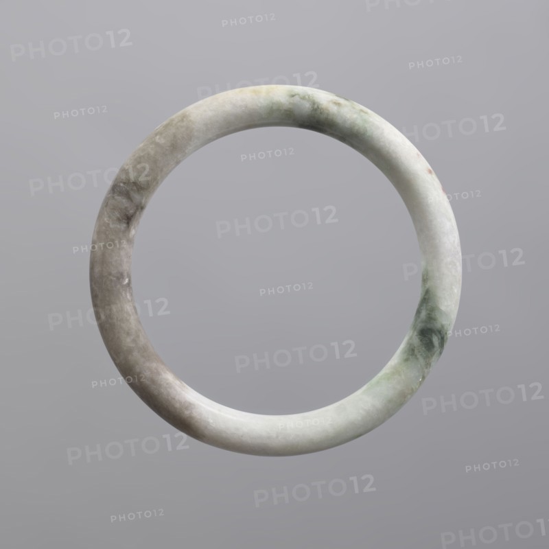 Bracelet, Chinese, Qing 1644–1911, women's jewelry, milky-white jadeite, opaque with green pigments, 19th century, China, jewelry, diameter 7.0 cm, A smooth circular stone ring suspended against a plain background, showing a mottled surface with shades of pale gray, white, light green, and faint beige, with subtle cloudy textures and polished highlights.
