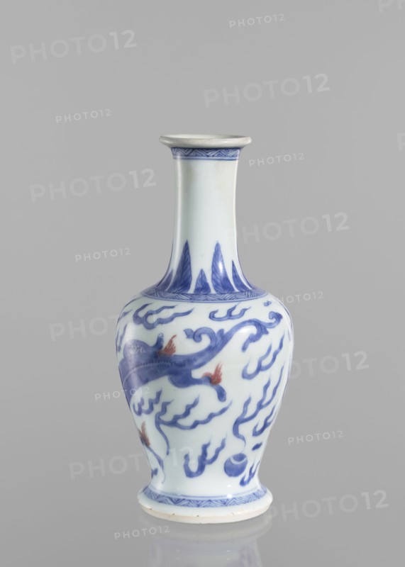 Vase, blue and white porcelain, Chinese art, Qing 1644–1911, 19th century, China; vessel with pearls and dragons iconography; height 19.6 cm, diameter 9.3 cm., A ceramic vase with a narrow neck and flared rim standing on a small round foot, predominantly white with blue painted decorative motifs and a few small areas of reddish-orange on the painted design, featuring flowing cloud-like patterns and stylized shapes; the background is a smooth neutral gray.