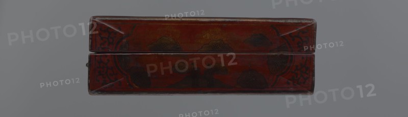 Box; maker, Chinese; Qing dynasty 1644–1911, early 20th century. Container, height 33.7 cm, width 19.5 cm, depth 6.7 cm. Material/decoration: Chinese art featuring landscape motifs with staffage, boats, figural scenes, scholars/sages, defensive walls architectural, and swastikas., A rectangular, closed wooden box with a hinged lid sits centered against a neutral gray background; the box is predominantly deep red with areas of darker red and brown patina, and it has black decorative motifs along the corners and edges as well as darker, nearly black floral or cloud-like shapes on the top surfaces, with small worn spots revealing lighter wood tones and a few scuffed edges.