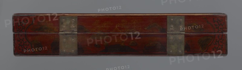 Box, gift; Chinese art, Qing 1644–1911 style, early 20th century, China. Lacquer container with figural scenes including scholars/sages, staffage, boats, defensive walls, landscape motifs, and swastikas. Height 33.7 cm, width 19.5 cm, depth 6.7 cm., A long rectangular wooden box with a hinged lid, shown closed and viewed from the front, finished in a deep red with darker red and black decorative motifs and painted landscape elements, a few areas of brown and golden paint creating mountain and cloud shapes, and two rectangular metal hinge plates with a dull grayish-green patina fastened with round rivets.