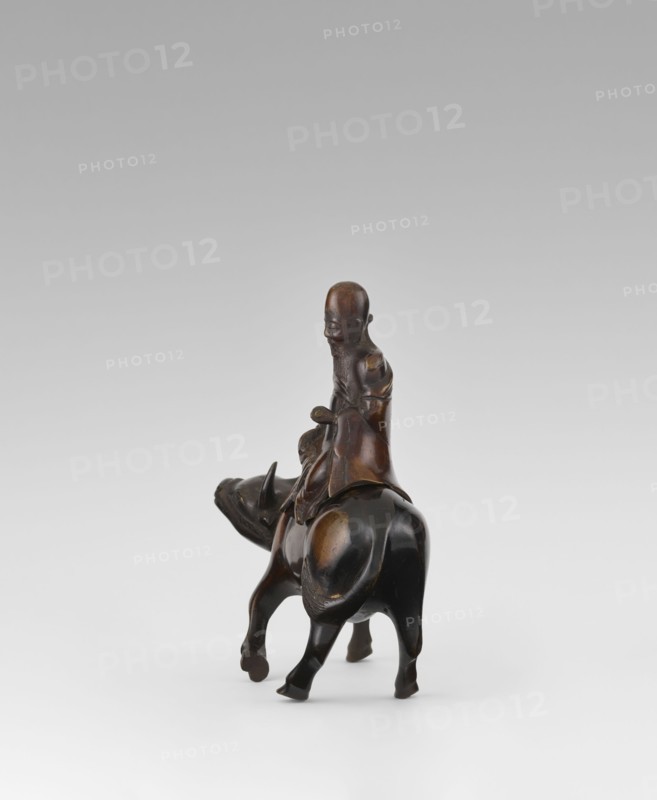 Shoulao on a buffalo - incense burner, Chinese, men, buffaloes, Taoism, incense burner, sage, Shouxing iconography, Qing dynasty 1644–1911, 19th century, China, sculpture/figurine, height 20.7 cm, width 20.7 cm, A dark brown carved figure of a person seated on the back of an animal resembling a water buffalo, both rendered in smooth, polished wood tones with lighter brown highlights on raised areas; the person has a rounded head, elongated facial features, a long beard, and draped clothing that falls over the animal's back, while the animal shows a sturdy body, curved horns, and four legs supporting the figure against a plain light gray to white gradient background.
