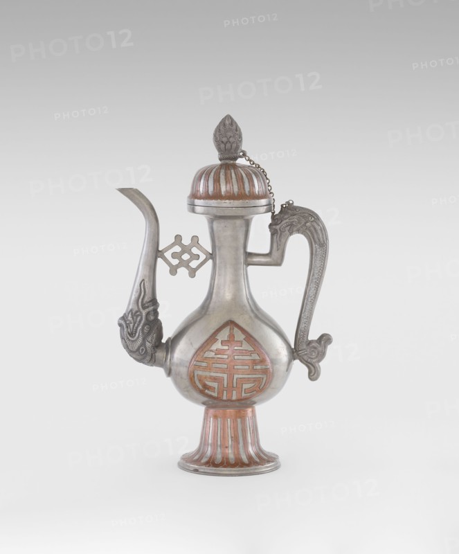 Wine jug, Chinese, plastic decorations of lotuses and longevity shou and dragons, Qing 1644–1911, early 20th century, China; vessel; height 26.8 cm, width 17.5 cm, An ornate metal vessel with a bulbous body, a long curved spout, and a tall handle is shown against a neutral background; the vessel has a domed lid topped with a finial and a short chain connecting lid to handle, decorative raised patterns on the spout and handle, a patterned recessed design on the body, and a flared foot with vertical ridges; visible colors include silver and copper tones, along with shades of gray.