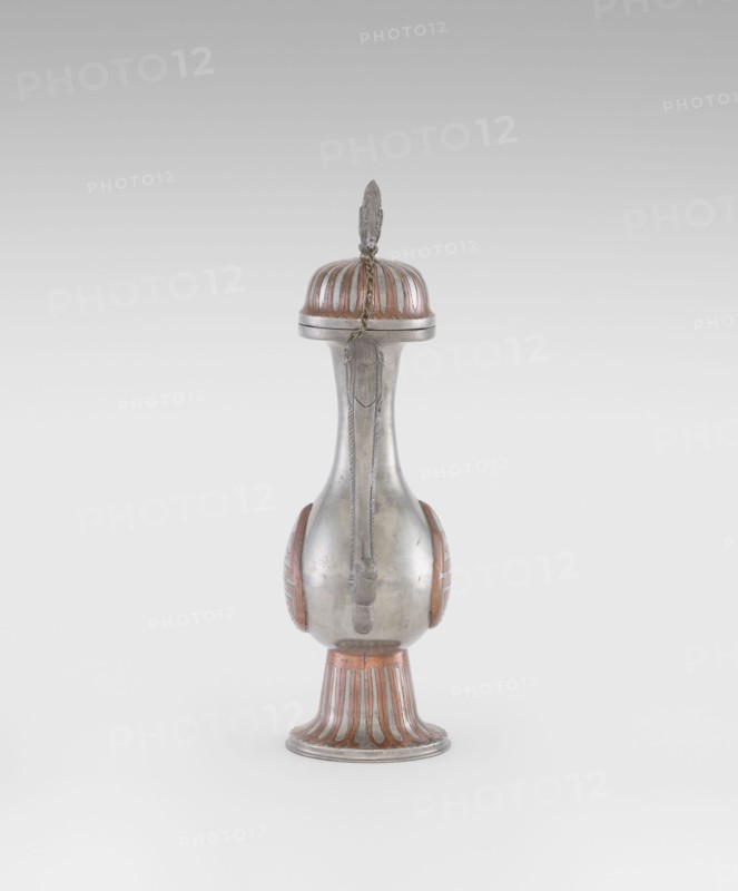 Wine jug, Chinese, plastic decorations of lotuses, longevity shou character, and dragons; Qing dynasty 1644–1911, early 20th century; ceramic vessel, height 26.8 cm, width 17.5 cm., A tall, narrow metallic vessel with a rounded base and slender neck topped by a domed lid and a decorative finial, showing a smooth silver surface with copper-colored accents on the lid, sides, and flared foot; a short decorative chain hangs from the lid down the neck, and the base and lid display fluted copper-colored panels contrasting with the silver body.